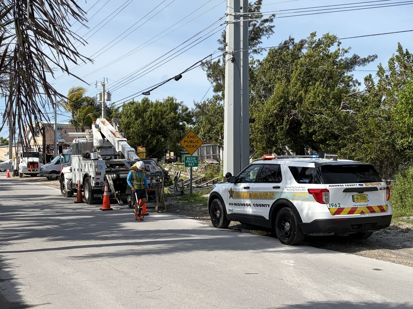 Monroe County Sheriff's Office vehicle beside a utility crew at a roadside work zone in the Florida Keys.